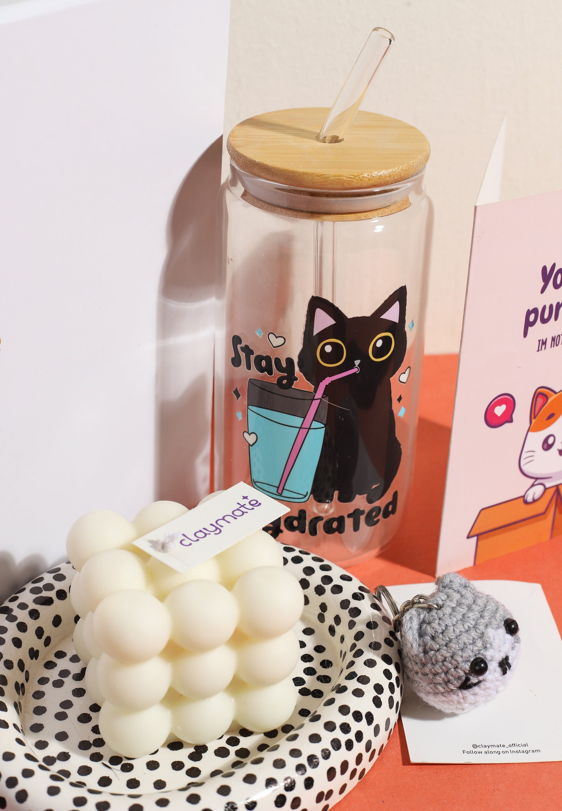 Cute cat-themed gift box featuring a ‘You are purr-fect’ greeting card, cat crochet keychain, bubble candle, black cat hydration tumbler, and polka dot ceramic dish on an orange background.