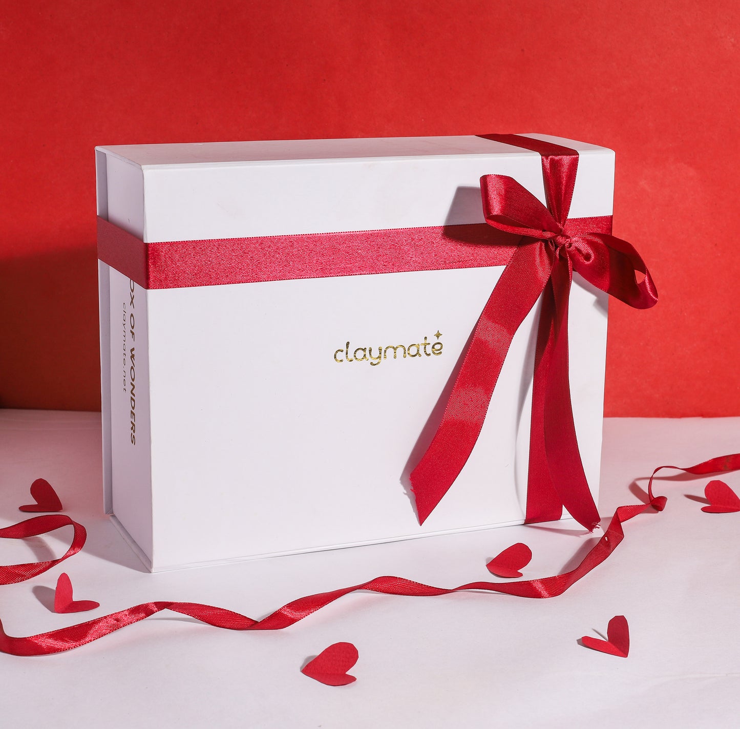A white magnetic gift box with a red ribbon and bow on top. The brand 'Claymate' is visible on the box.