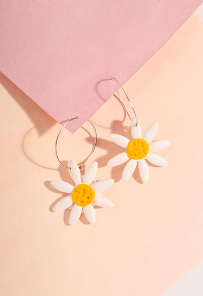 Daisy hoop earrings on a pink background