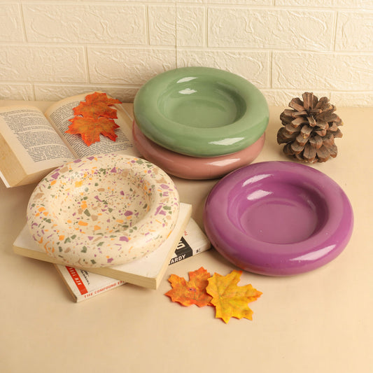 Set of colorful bowls on a textured surface with leaves and a book.